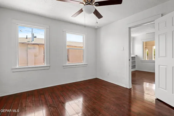 a view of empty room with wooden floor and fan