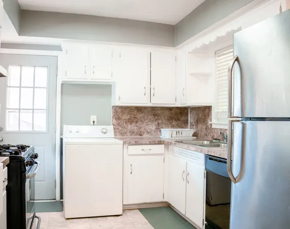 a kitchen with a sink a stove a refrigerator and white cabinets