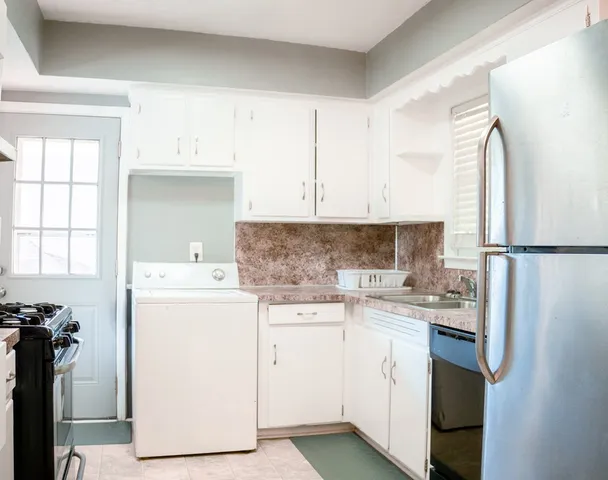 a kitchen with a sink a stove a refrigerator and white cabinets