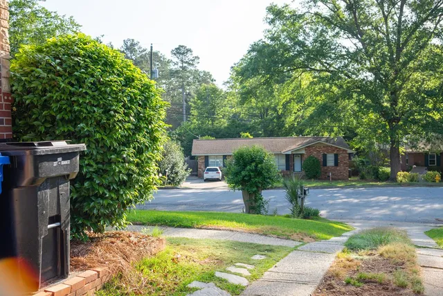 a front view of a house with a garden and trees