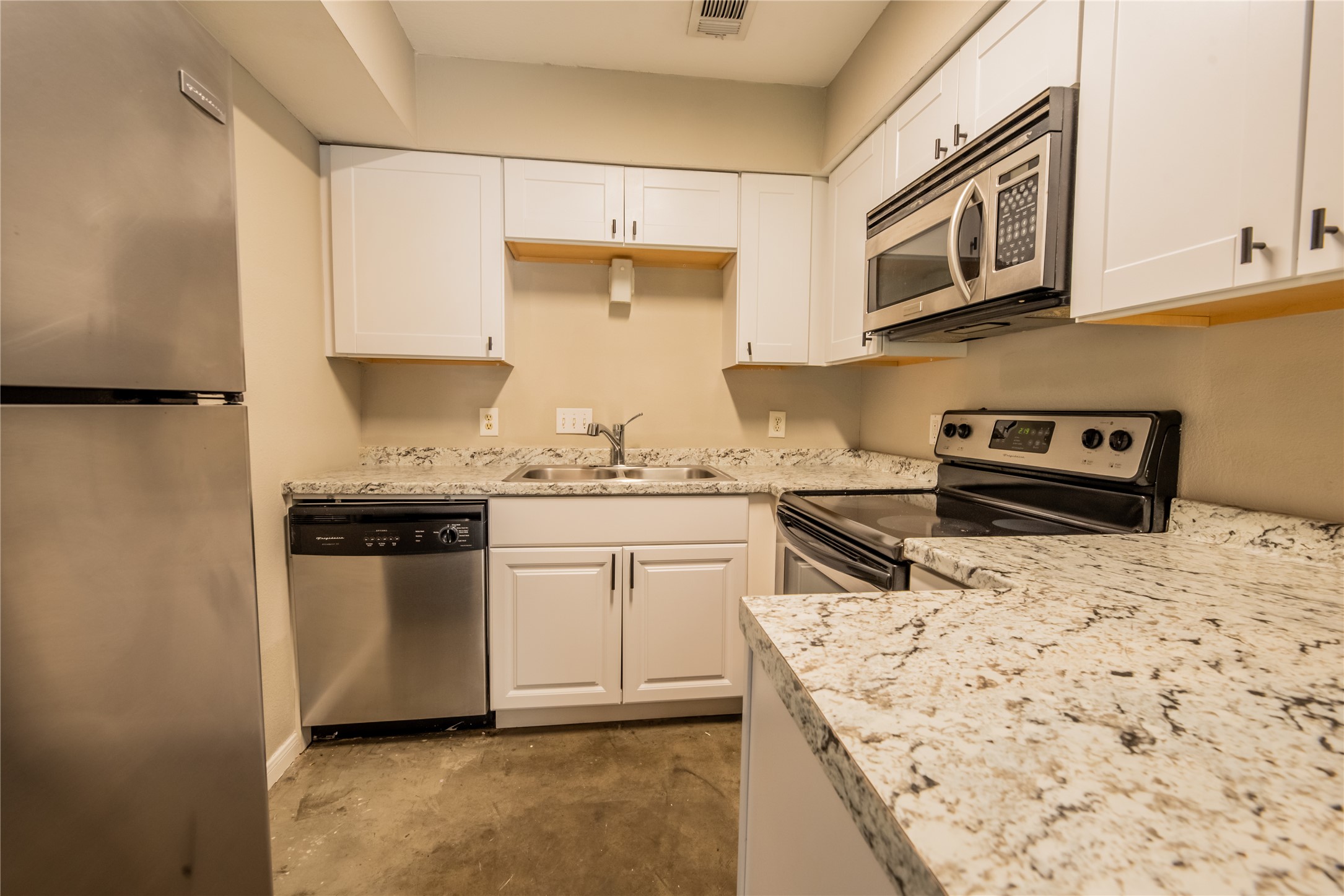 1013 West 23rd Street, Unit 201 Austin, TX 78705 - Photo 3 of 6 Kitchen with stainless steel appliances, white cabinetry, concrete floors and all appliances.