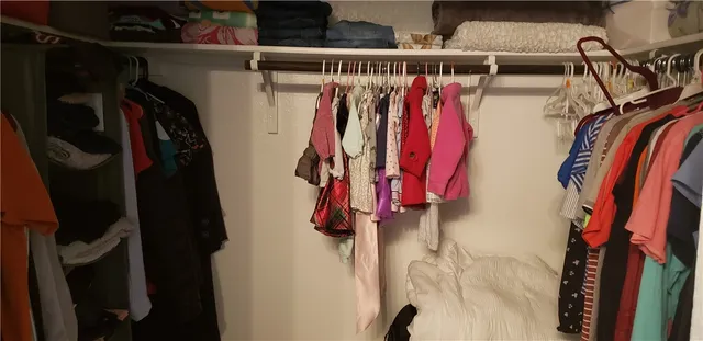 a view of walk in closet with clothes and shoes