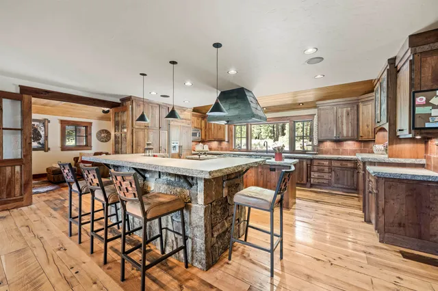 a kitchen with stainless steel appliances kitchen island granite countertop a table chairs sink and cabinets