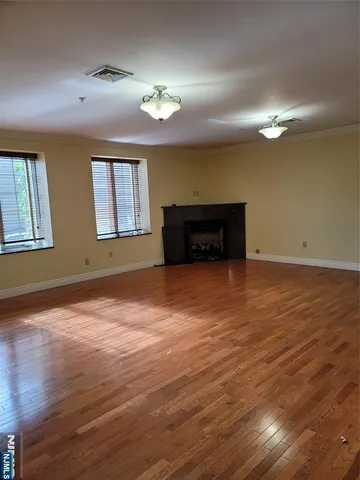 an empty room with wooden floor chandelier fan and windows