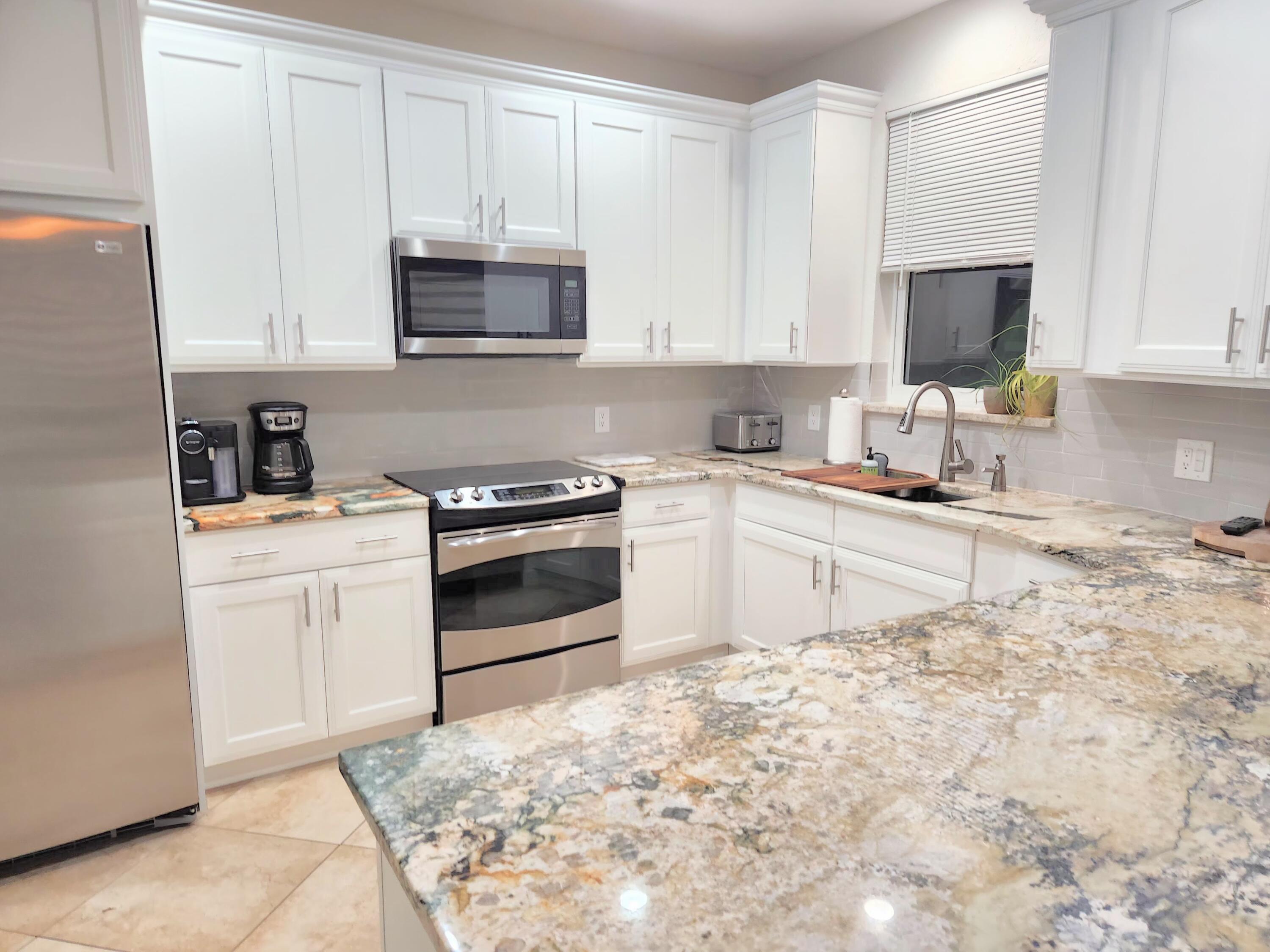 3567 Commodore Circle Delray Beach, FL 33483 - Photo 17 of 76 a kitchen with granite countertop a sink stove and microwave