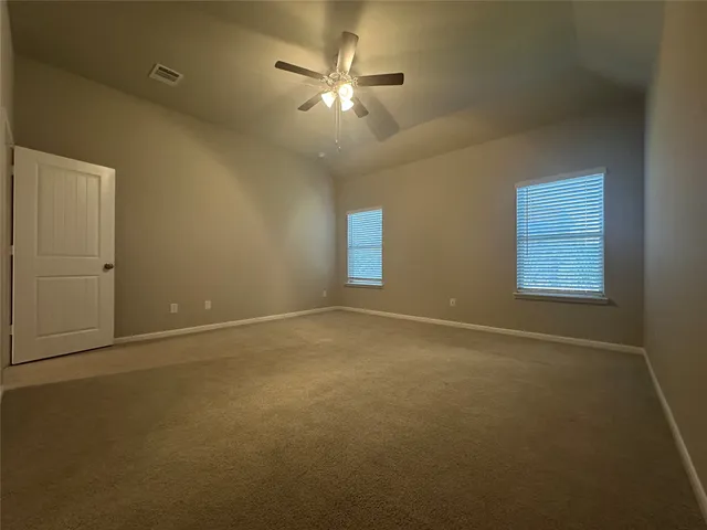an empty room with a ceiling fan and window