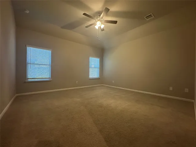 an empty room with windows and fan