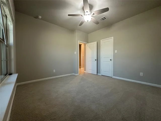 an empty room with a ceiling fan and a window