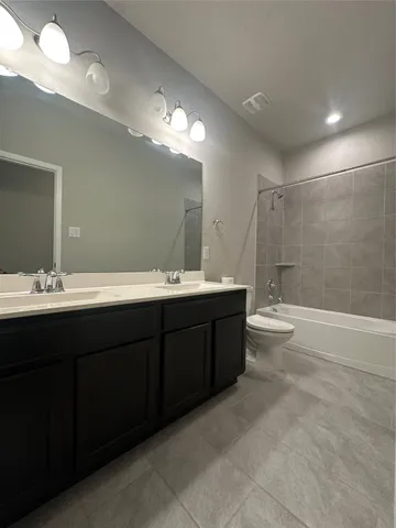 a bathroom with a double vanity sink a large mirror and a bathtub