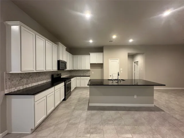a large kitchen with kitchen island a large counter top stainless steel appliances and cabinets