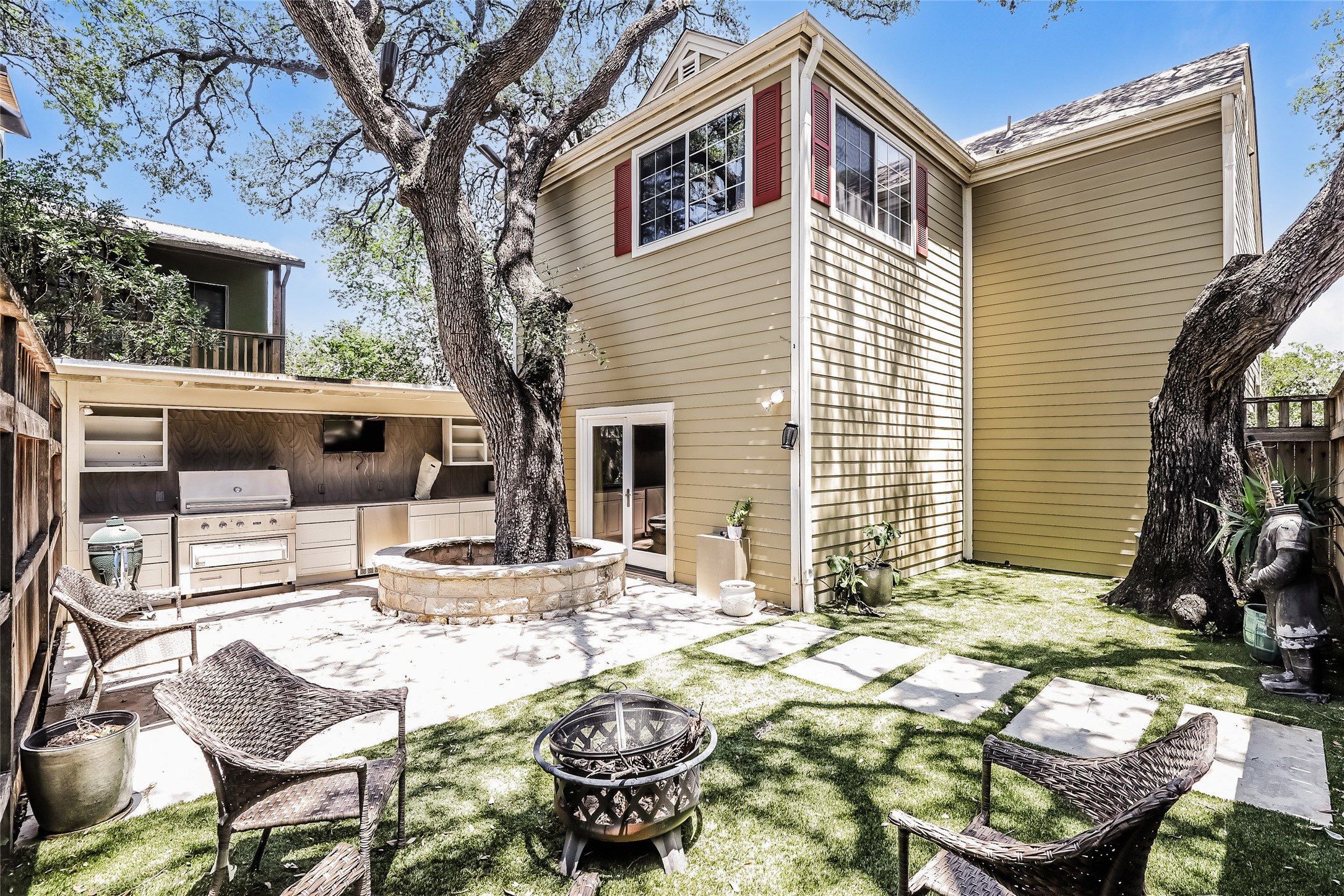 1702 Newning Avenue, Unit A Austin, TX 78704 - Photo 20 of 20 Expansive outdoor living area featuring a built-in outdoor kitchen with stainless steel appliances, a stone-lined tree planter, a patio area, and a grass lawn with stepping stones