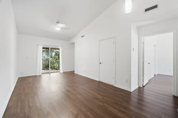 an empty room with wooden floor and windows