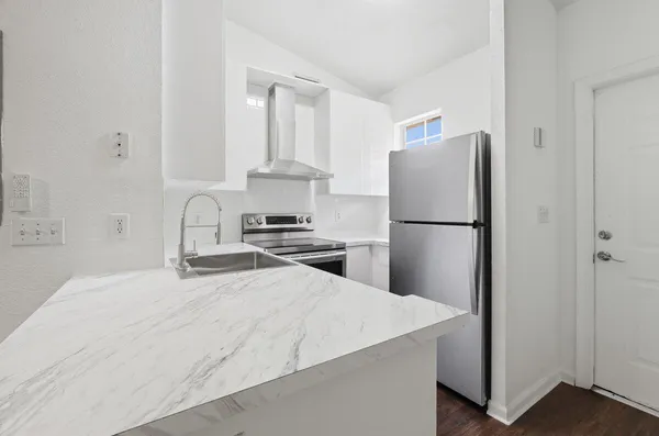 a kitchen with a refrigerator a stove and white cabinets