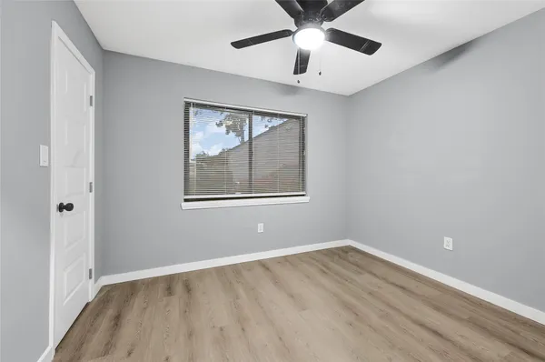 an empty room with a window and ceiling fan