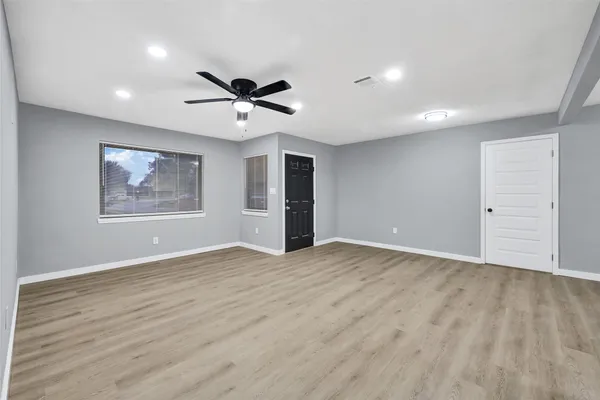 a view of an empty room with a window and wooden floor