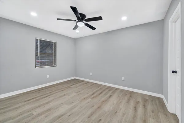 an empty room with wooden floor ceiling fan and windows