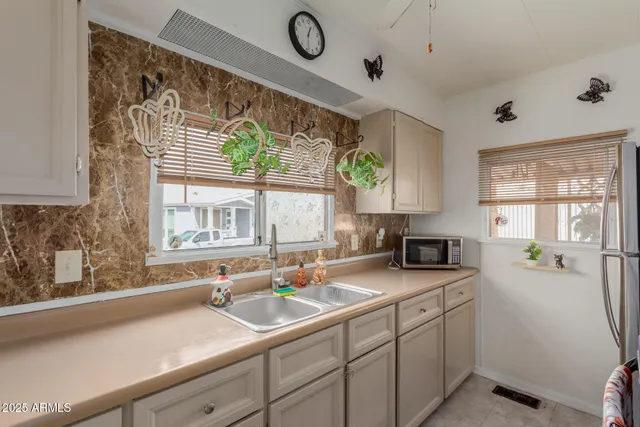 a kitchen with a sink appliances cabinets and a large window