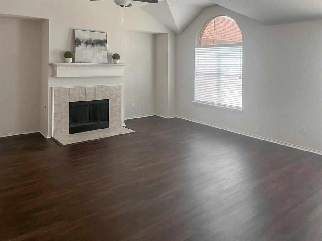 9305 Amber Downs Drive McKinney, TX 75072 - Photo 10 of 28 an empty room with wooden floor a fireplace and windows