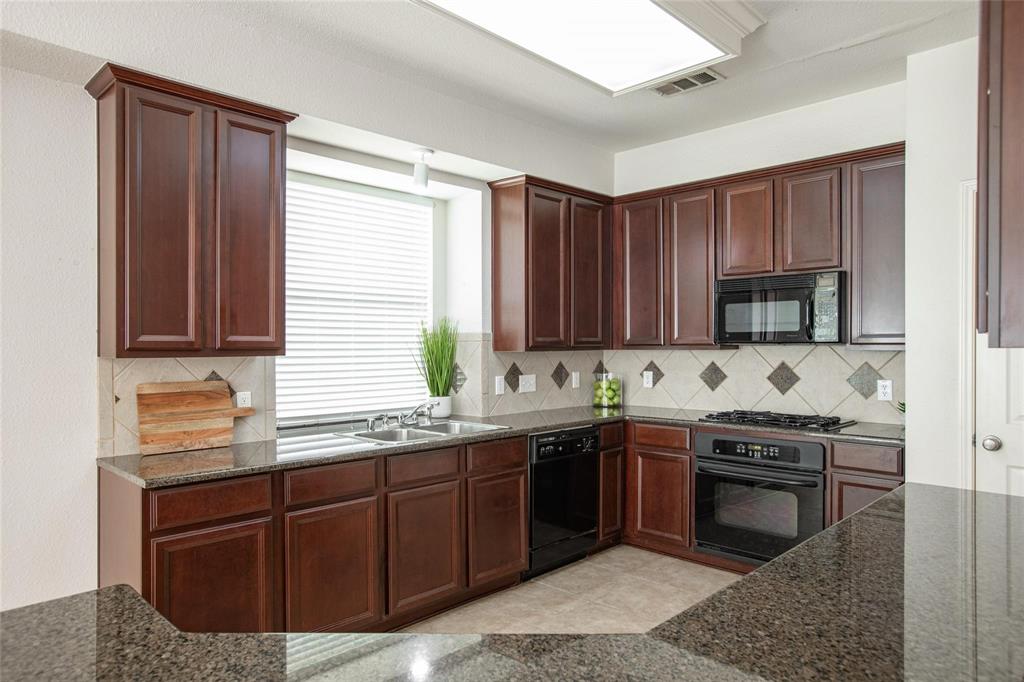9305 Amber Downs Drive McKinney, TX 75072 - Photo 5 of 28 a kitchen with stainless steel appliances granite countertop wooden cabinets a sink and a stove