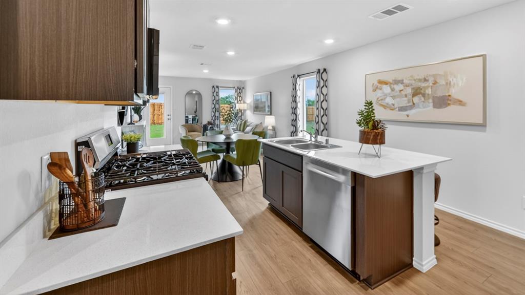 3514 Spring Time Street Terrell, TX 75126 - Photo 8 of 26 Modern kitchen featuring a gas range, white countertops, dark wood-finish cabinetry, stainless steel appliances, and wood-finish flooring