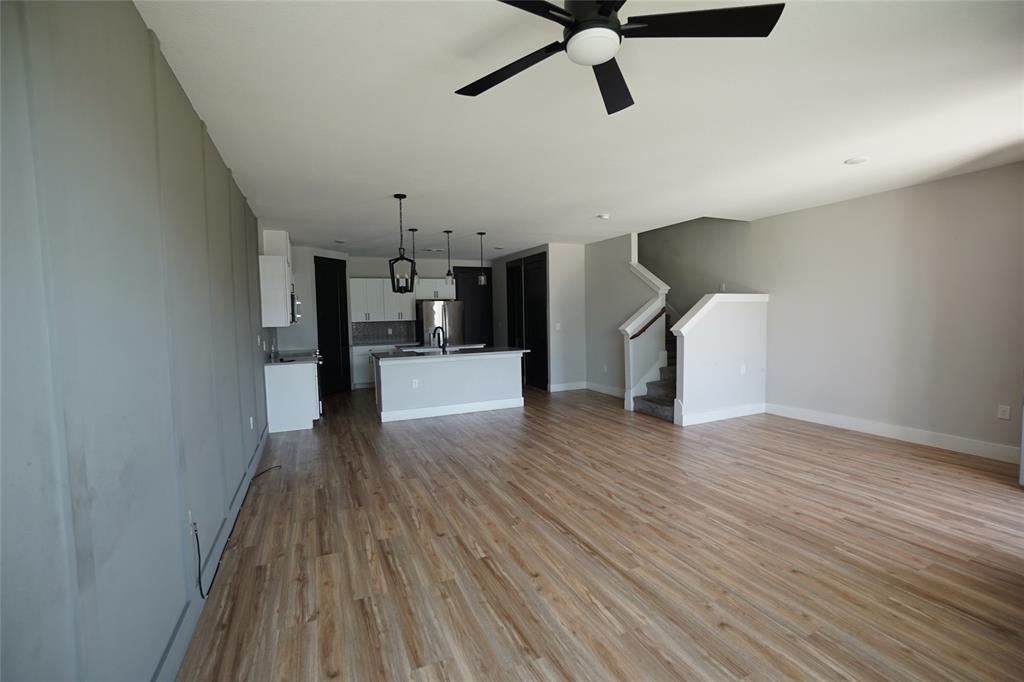 1764 Palladio Loop Princeton, TX 75407 - Photo 3 of 40 Open-concept living space featuring wood-finish flooring, a modern kitchen with a central island, stainless steel appliances, and pendant lighting