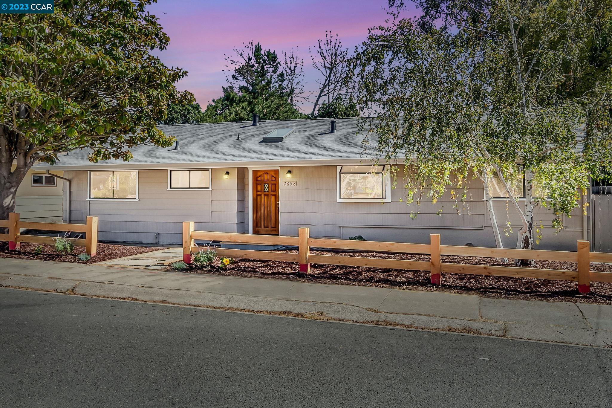 a view of a house with a yard and a large tree