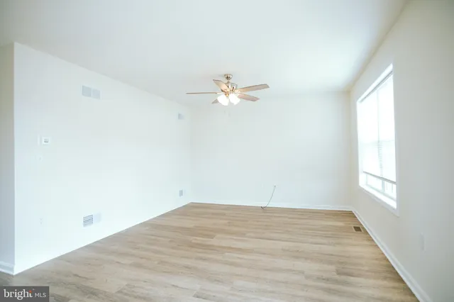 an empty room with a window and a ceiling fan
