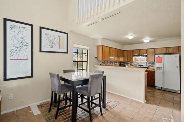 a kitchen with a dining table chairs and refrigerator
