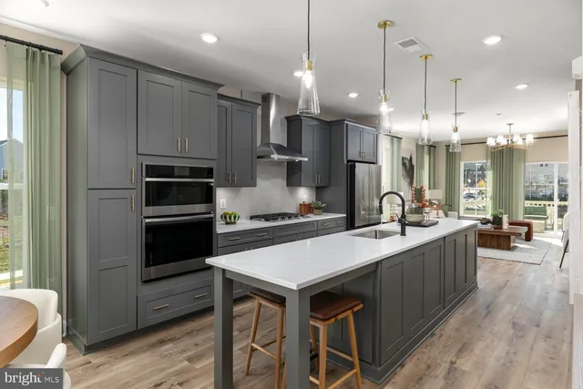 a open kitchen with stainless steel appliances granite countertop a kitchen island a stove a refrigerator a oven and a sink with wooden floor