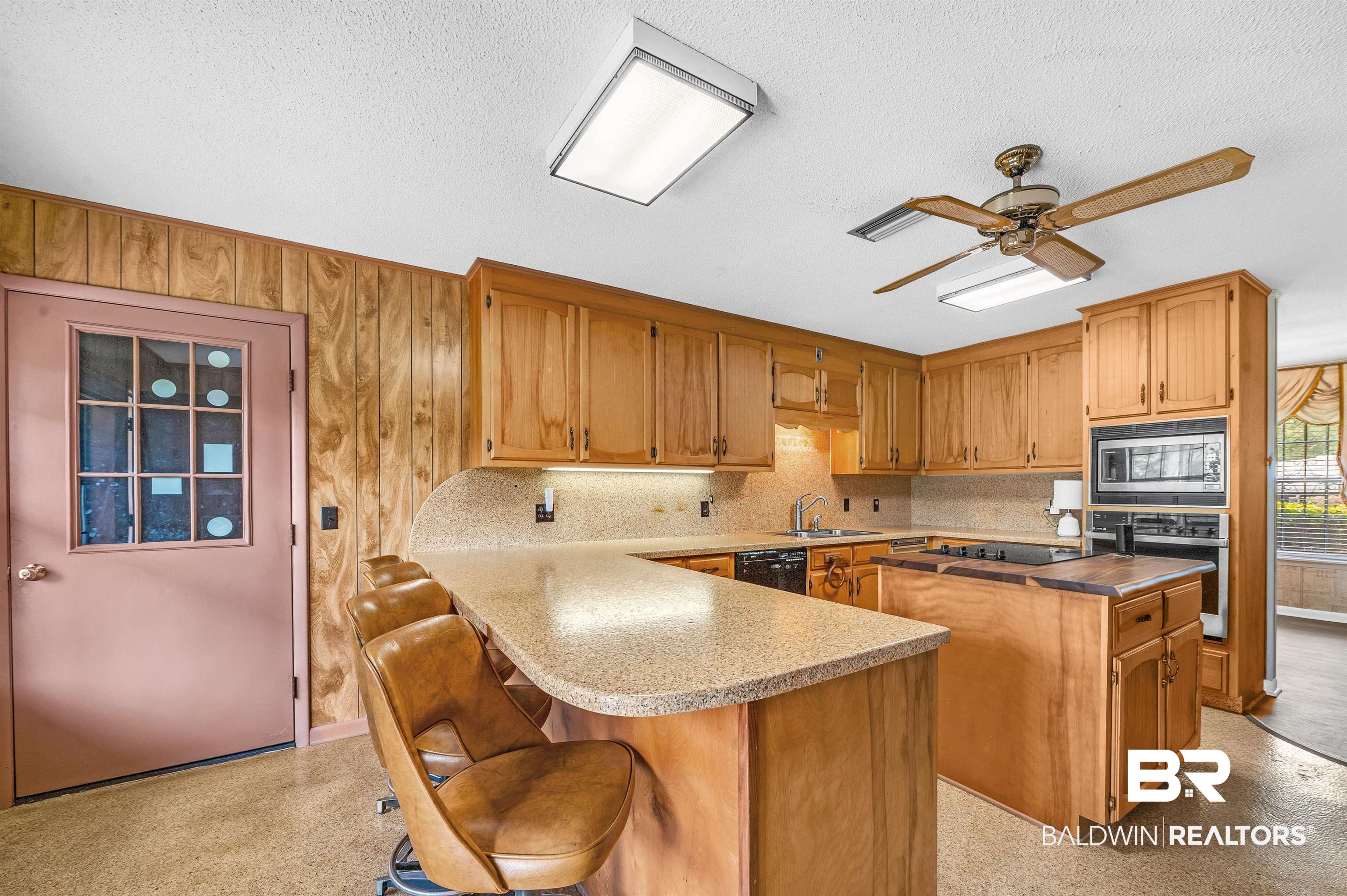 610 East Walker Avenue Foley, AL 36535 - Photo 16 of 38 Kitchen with black appliances, a kitchen island, a textured ceiling, brown cabinets, and a ceiling fan