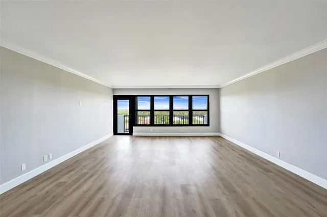 a view of an empty room with wooden floor and closet