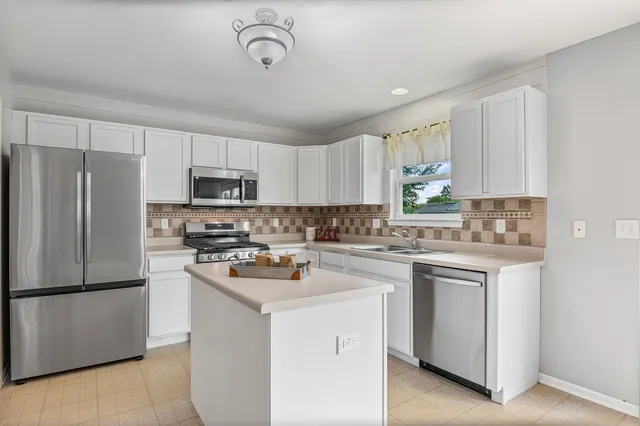 a kitchen with a sink a stove a refrigerator cabinets and a window