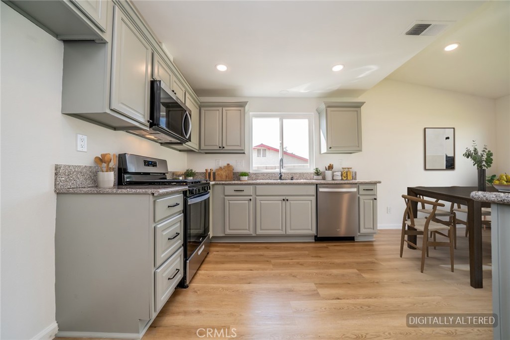 818 Terrace Road San Bernardino, CA 92410 - Photo 13 of 44 a kitchen with stainless steel appliances granite countertop a stove top oven a sink dishwasher and white cabinets with wooden floor