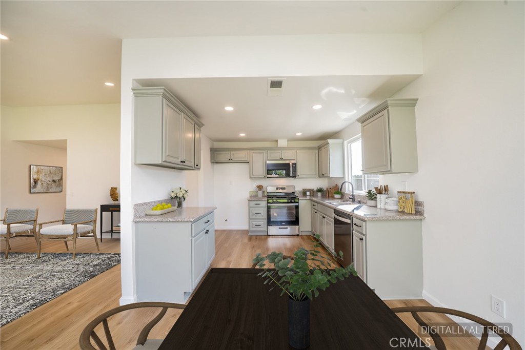 818 Terrace Road San Bernardino, CA 92410 - Photo 9 of 44 a kitchen with stainless steel appliances granite countertop a stove top oven a sink dishwasher and white cabinets with wooden floor