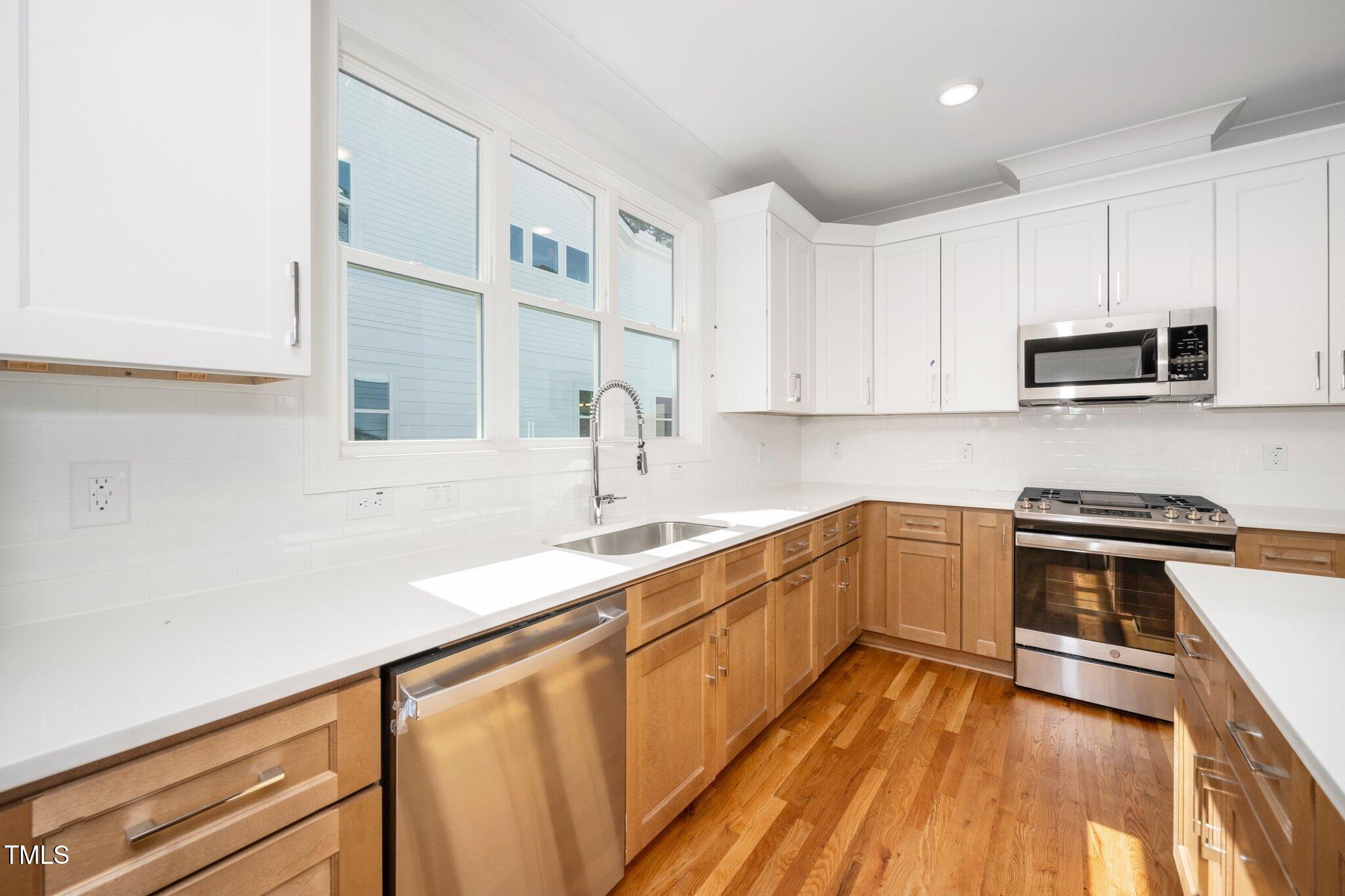 1211 Chaney Road Raleigh, NC 27606 - Photo 12 of 36 a kitchen with stainless steel appliances a sink dishwasher stove and oven with wooden floor