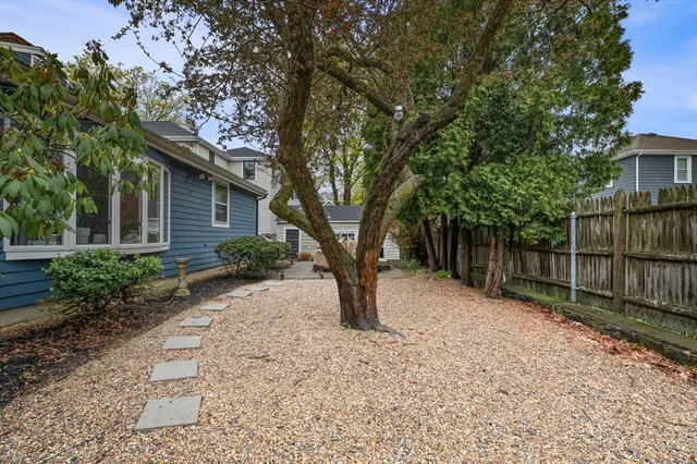 a view of a backyard with wooden fence and large trees