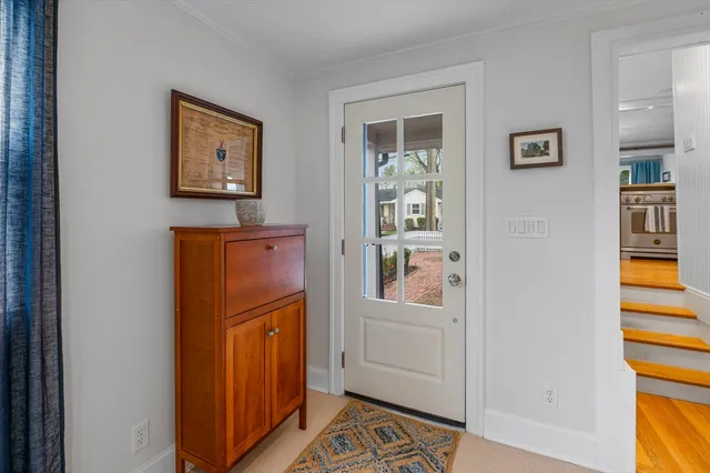 a view of a hallway to a livingroom with wooden floor and windows