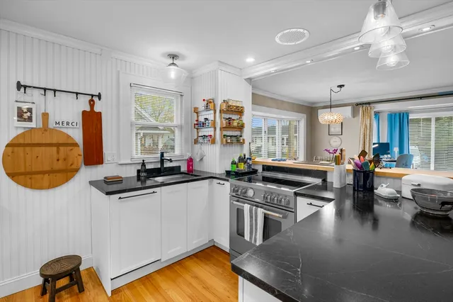 a kitchen with stainless steel appliances granite countertop a stove a sink dishwasher a dining table and chairs with wooden floor