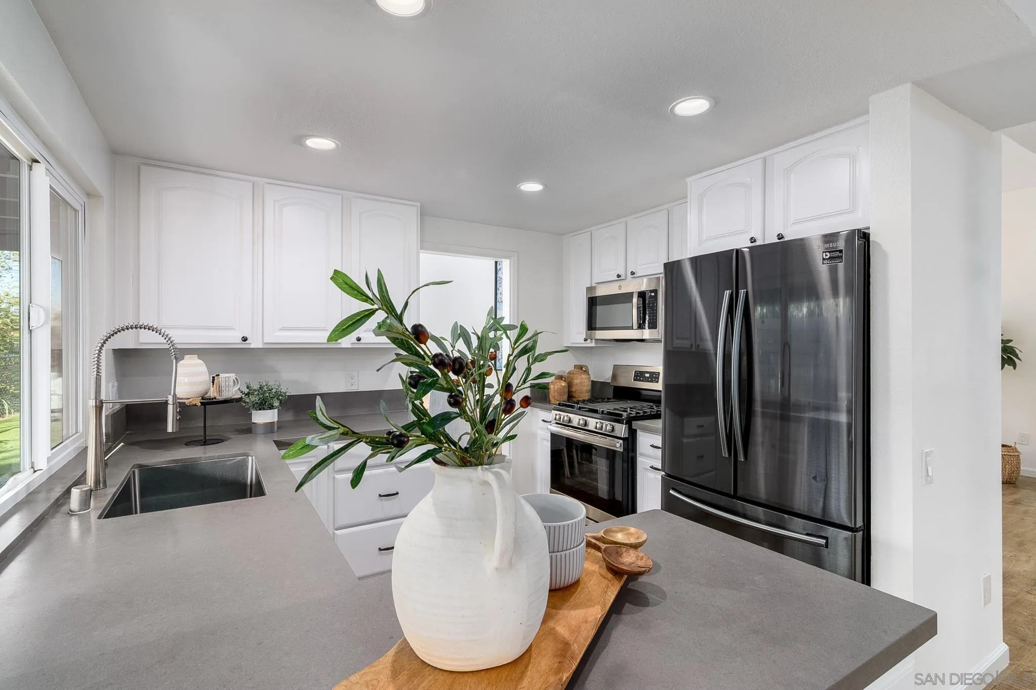 16556 Gabarda Road San Diego, CA 92128 - Photo 14 of 42 a kitchen with stainless steel appliances a sink a counter cabinets and a dining table