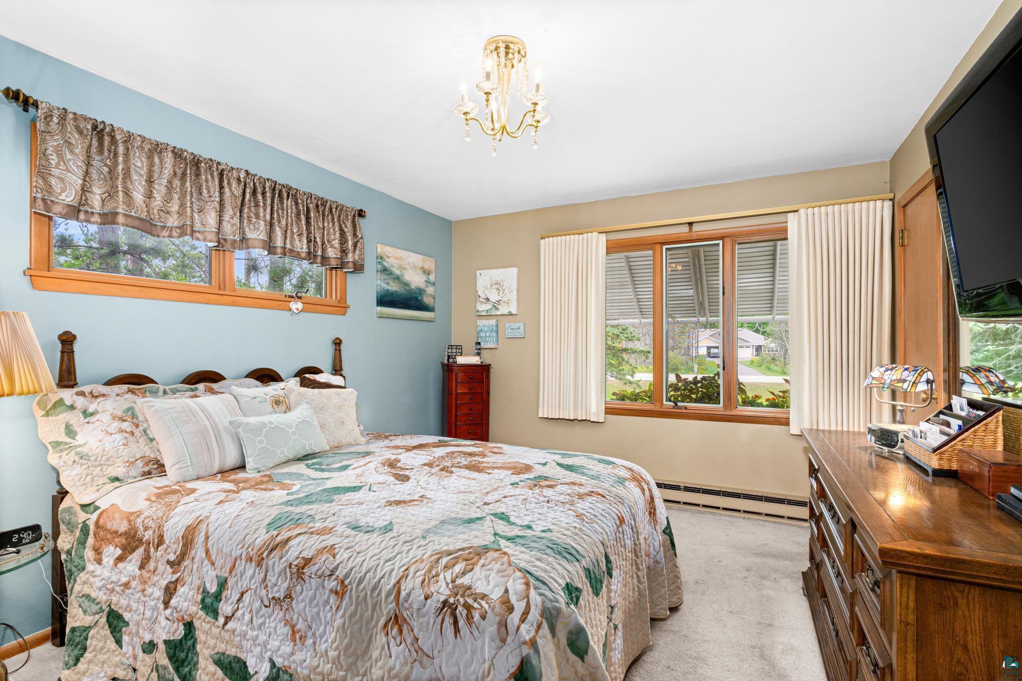 3727 Stebner Road Hermantown, MN 55811 - Photo 19 of 41 Carpeted bedroom with a chandelier, wood-framed windows, and a built-in baseboard heater