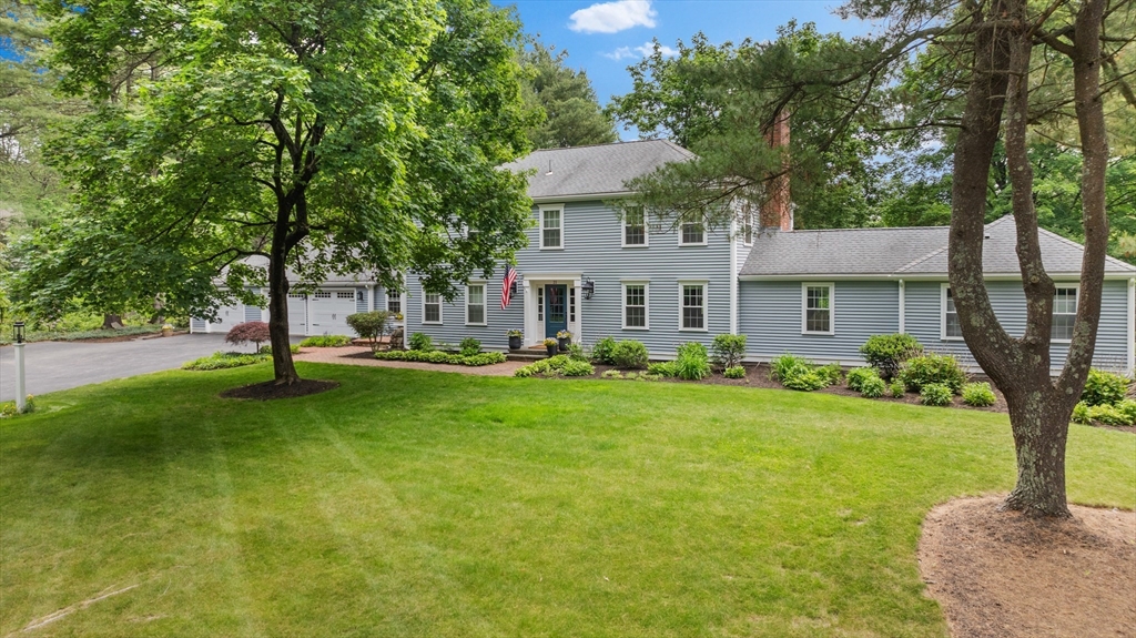 a front view of a house with a yard and tree
