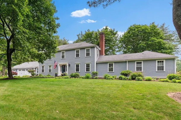 a white house with a big yard and potted plants in front of it