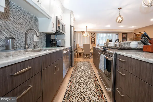 a kitchen with stainless steel appliances granite countertop a sink a stove and a wooden cabinets