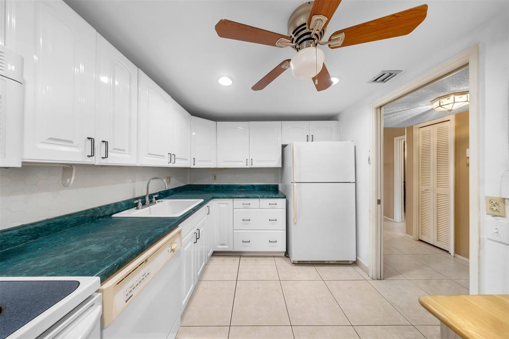 2681 South Course Drive, Unit 301 Pompano Beach, FL 33069 - Photo 2 of 27 a kitchen with granite countertop a white refrigerator oven a stove and white cabinets with wooden floor