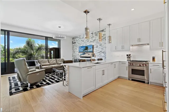 a kitchen with stainless steel appliances granite countertop a stove a sink dishwasher a refrigerator and white cabinets with wooden floor