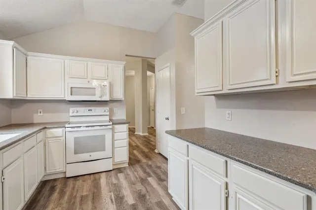 a kitchen with granite countertop white cabinets and white appliances