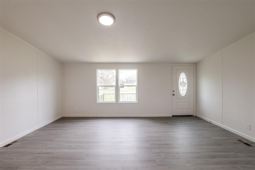 945 Walnut Street Azle, TX 76020 - Photo 5 of 29 an empty room with wooden floor and windows