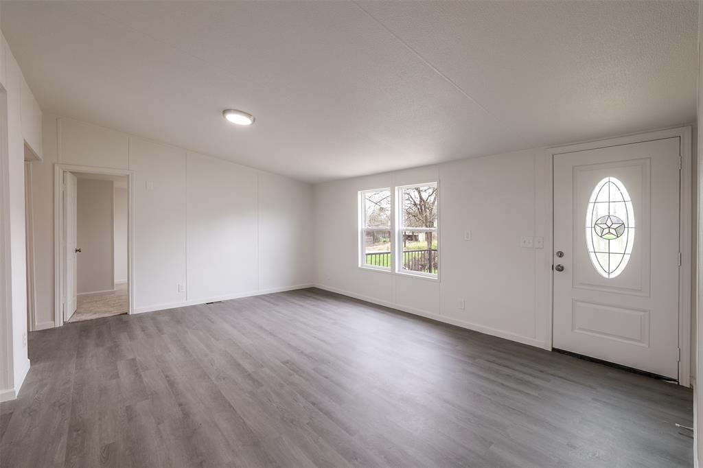 945 Walnut Street Azle, TX 76020 - Photo 6 of 29 an empty room with wooden floor cabinet and windows