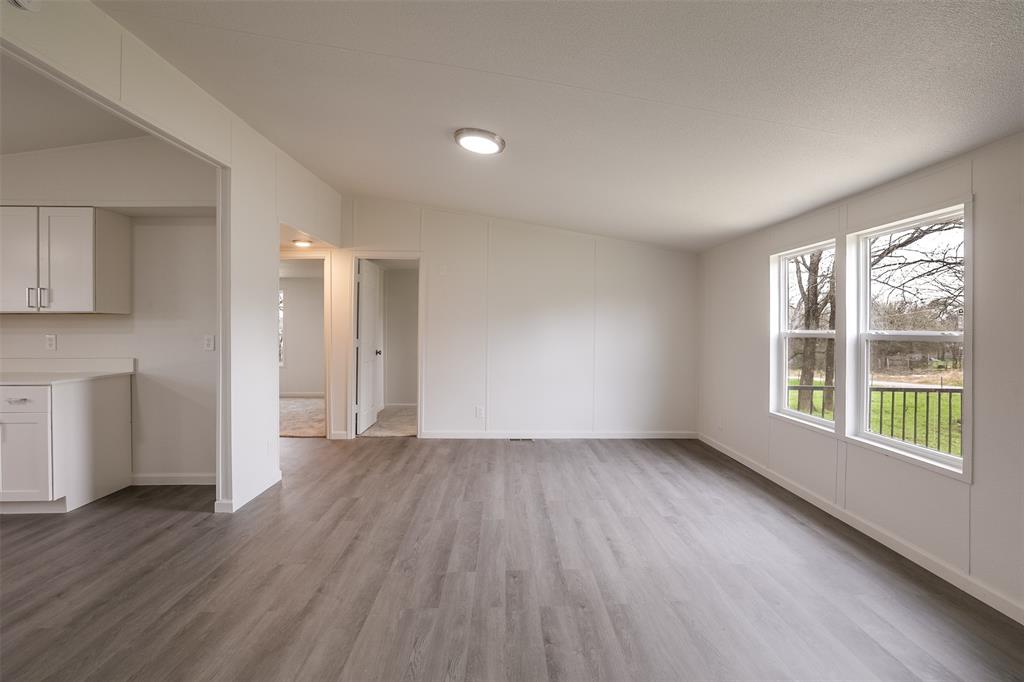 945 Walnut Street Azle, TX 76020 - Photo 7 of 29 a view of an empty room with wooden floor and a window