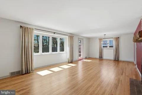 a view of an empty room with window and wooden floor